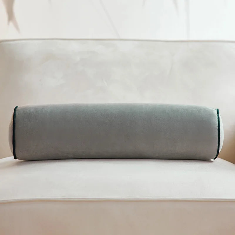 1. Coussin cylindrique gris en velours posé sur un canapé crème.