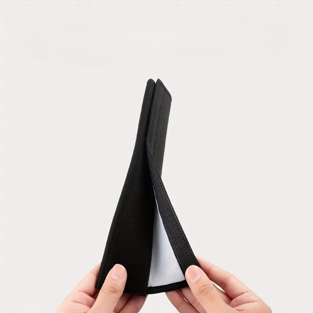 Coussin de ceinture de sécurité noir, plié, avec une texture douce, tenant entre les mains sur fond neutre