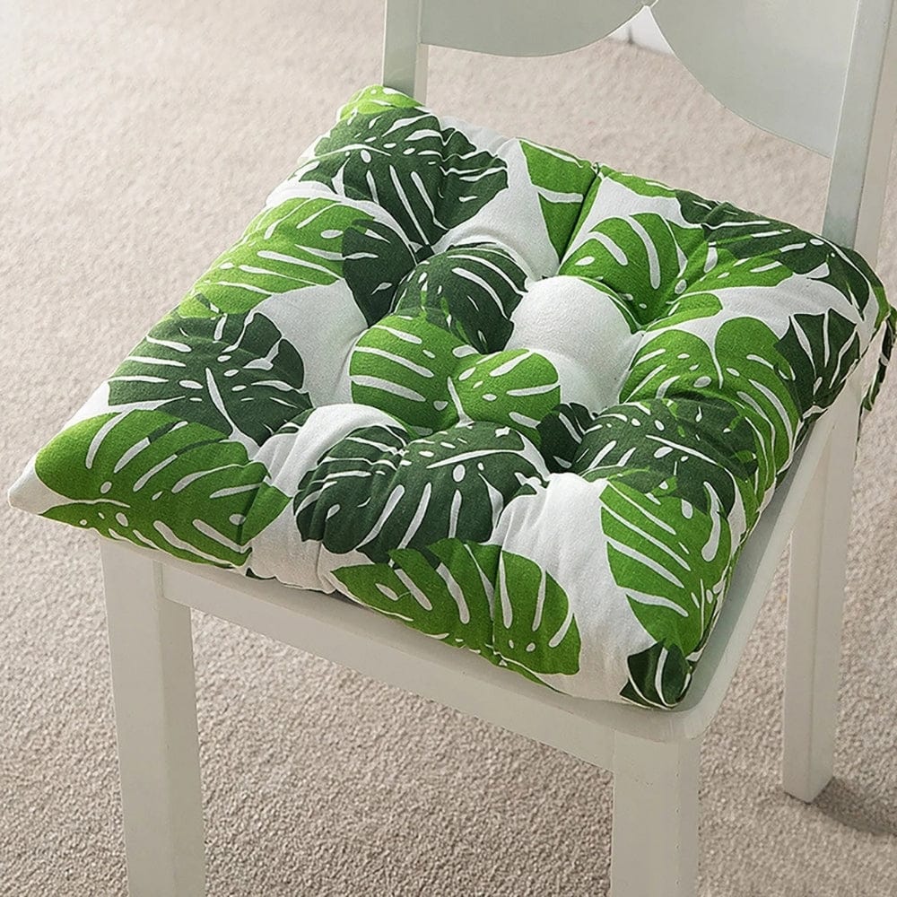 Coussin de chaise de jardin avec motifs de feuilles vertes sur fond blanc, posé sur une chaise en bois