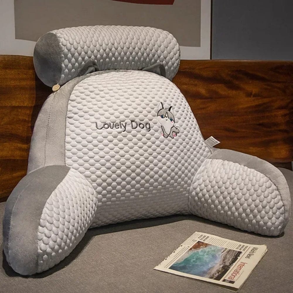 Coussin de lecture gris et blanc avec accoudoirs, placé sur un lit, offrant un confort optimal pour la détente