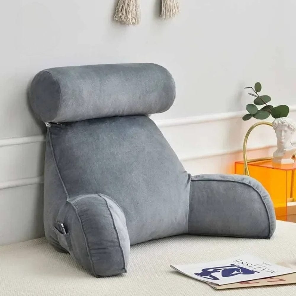Coussin de lecture gris en velours, avec un dossier haut et des accoudoirs, posé sur un tapis dans un salon