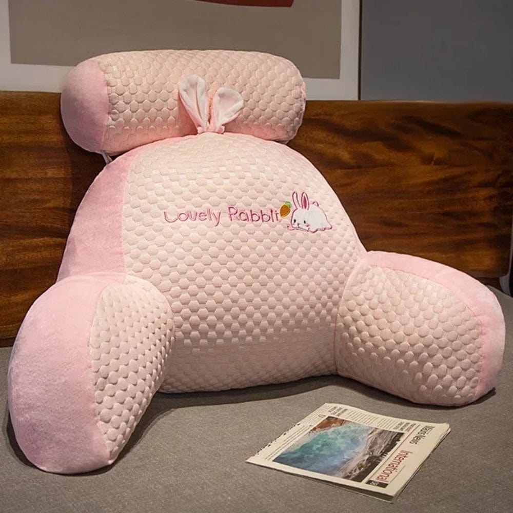 Coussin de lecture en velours rose avec motifs en relief, posé sur un lit, décoré d'un motif de lapin