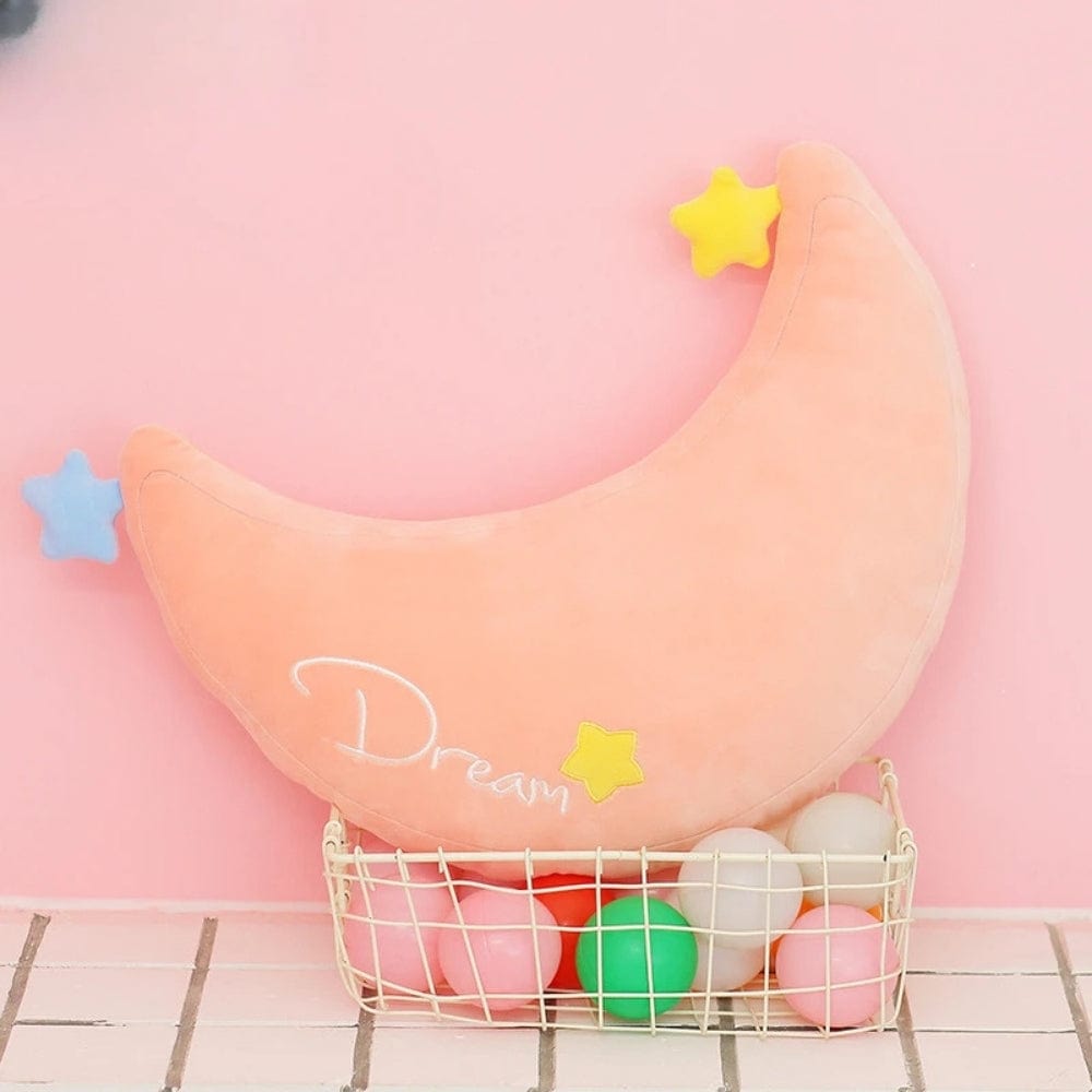 Coussin décoratif en forme de demi-lune rose avec étoiles colorées, posé dans un panier en métal