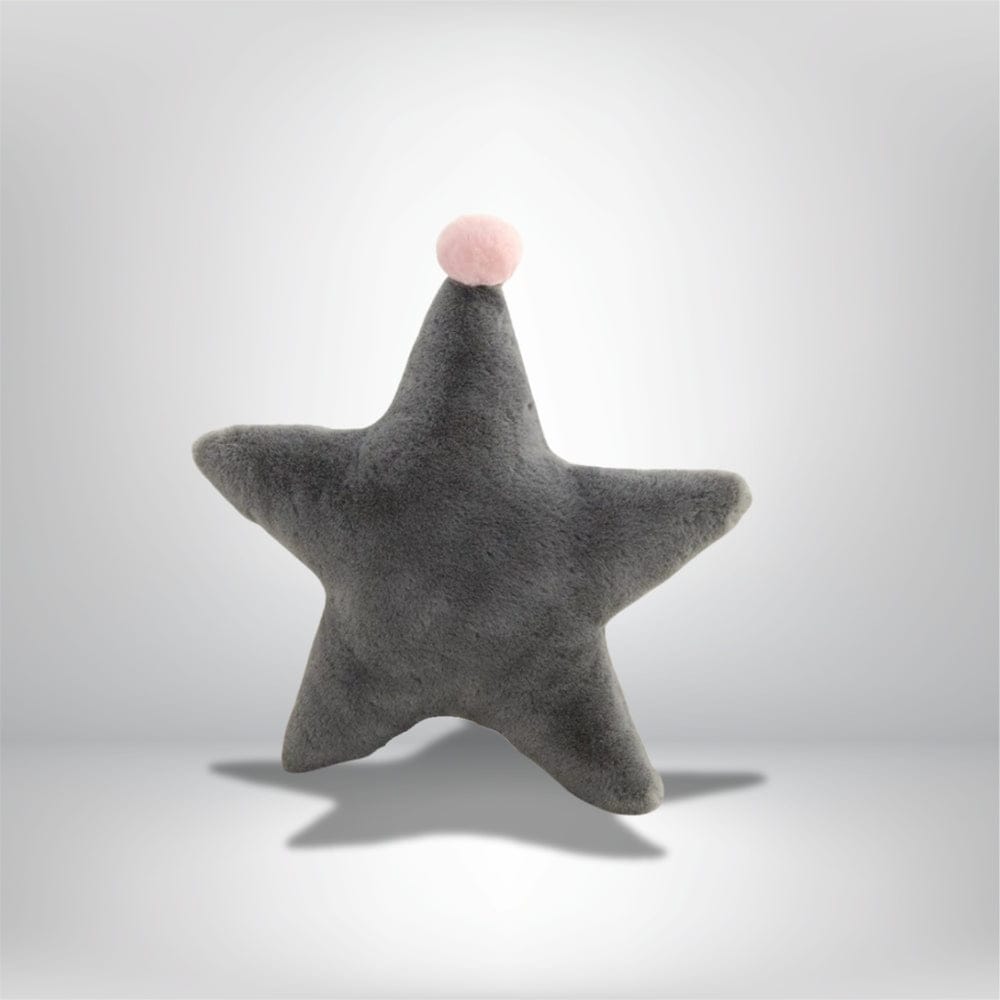 Coussin décoratif en forme d'étoile gris avec un pompon rose, posé sur un fond neutre