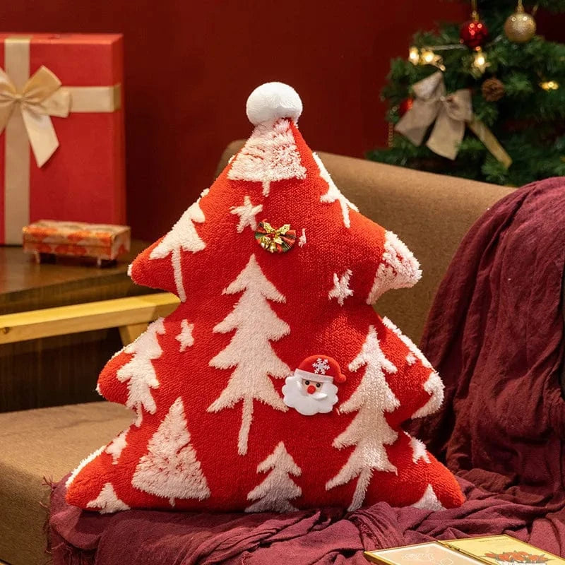 Coussin décoratif en forme de sapin rouge avec des motifs blancs, posé sur un canapé, ambiance festive et chaleureuse
