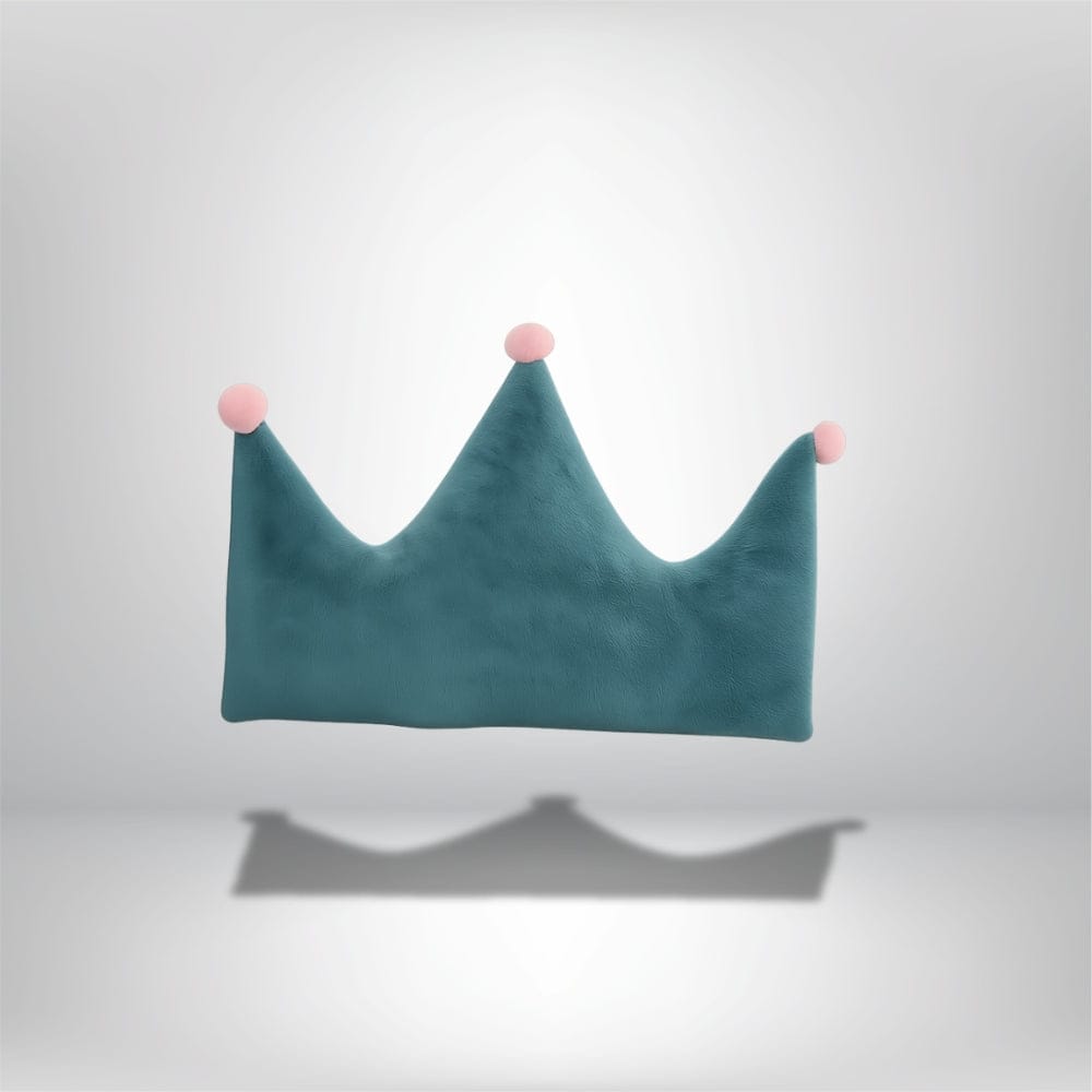 Coussin décoratif en forme de couronne, en velours bleu avec pompons roses, sur fond neutre