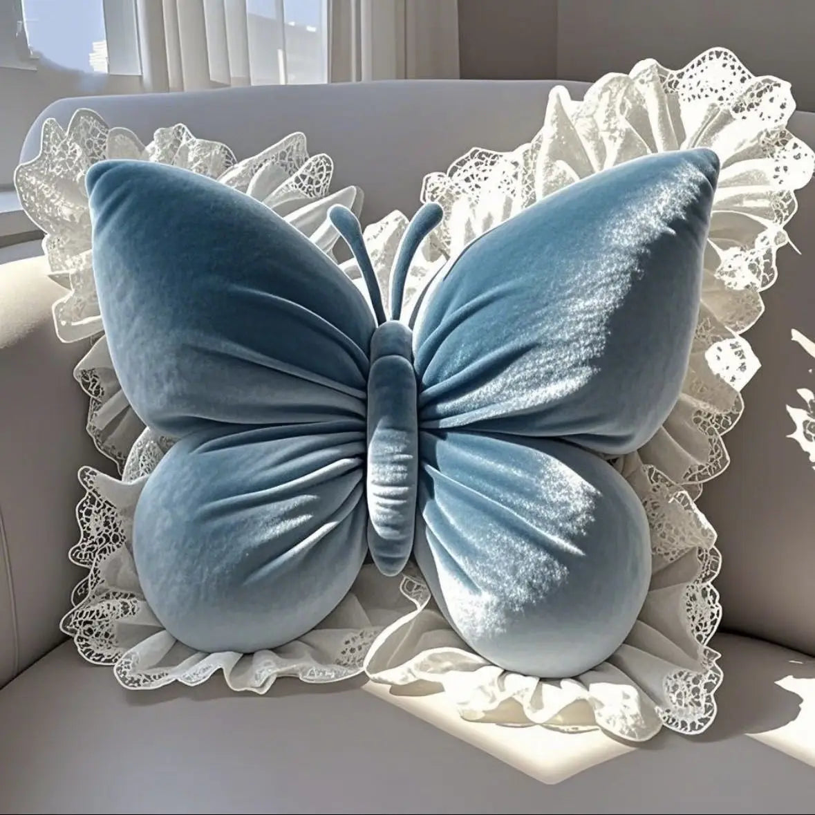 Coussin décoratif en velours bleu en forme de papillon avec une bordure en dentelle blanche sur un canapé