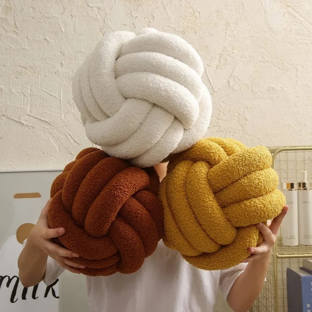 Coussins décoratifs ronds en tissu doux, couleurs crème, marron et jaune, présentés dans un salon moderne