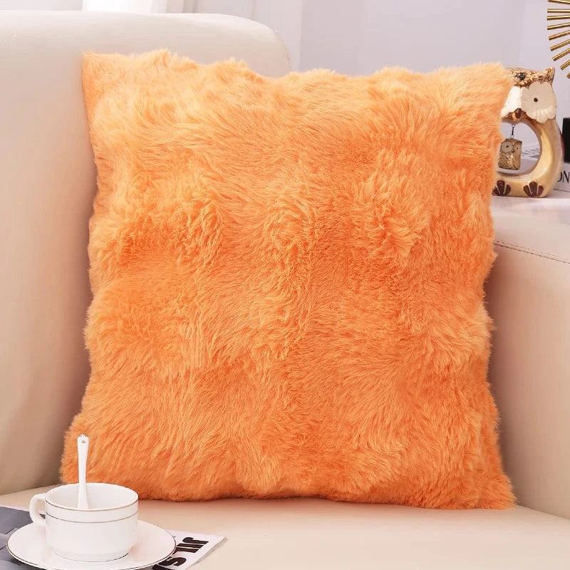 Coussin décoratif en fausse fourrure orange, posé sur un canapé, créant une ambiance cocooning et chaleureuse