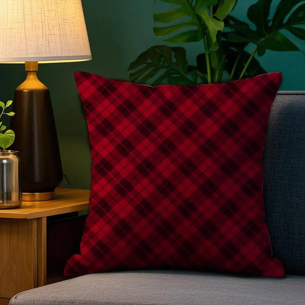 Coussin décoratif en tartan rouge posé sur un canapé, avec une lampe et une plante en arrière-plan