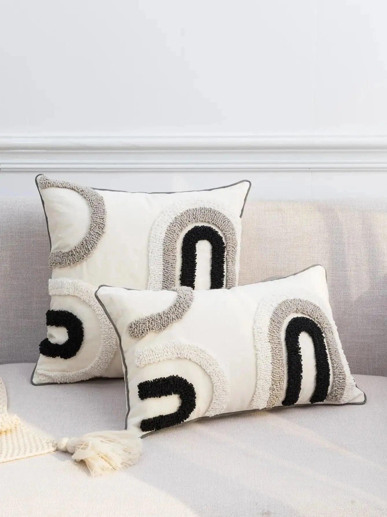 Housse de coussin décoratif aux motifs abstraits noir, blanc et gris sur un canapé moderne