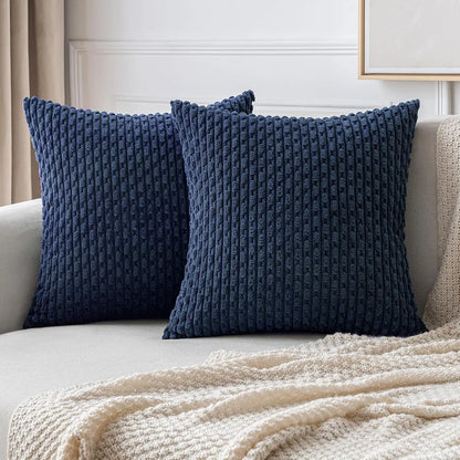 Deux housses de coussin bleu marine à relief côtelé présentées dans une décoration lumineuse.