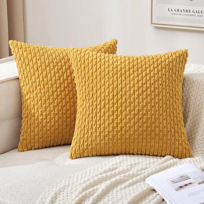 Deux housses de coussin jaune moutarde à relief côtelé présentées sur un canapé clair.
