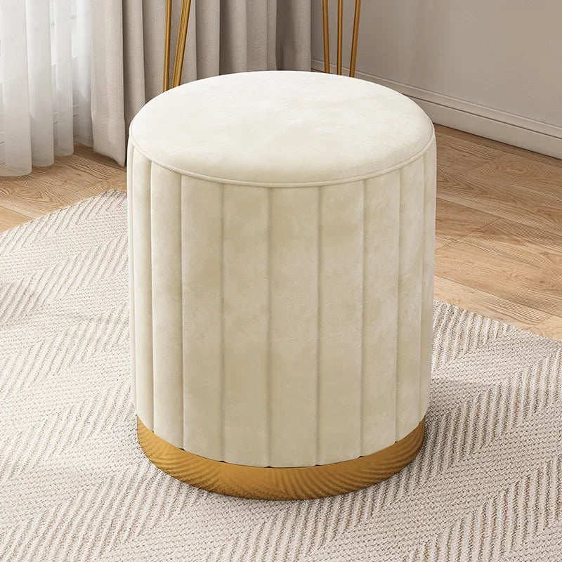 Vue légèrement en plongée du pouf blanc crème en velours montrant son assise ronde et sa base dorée.