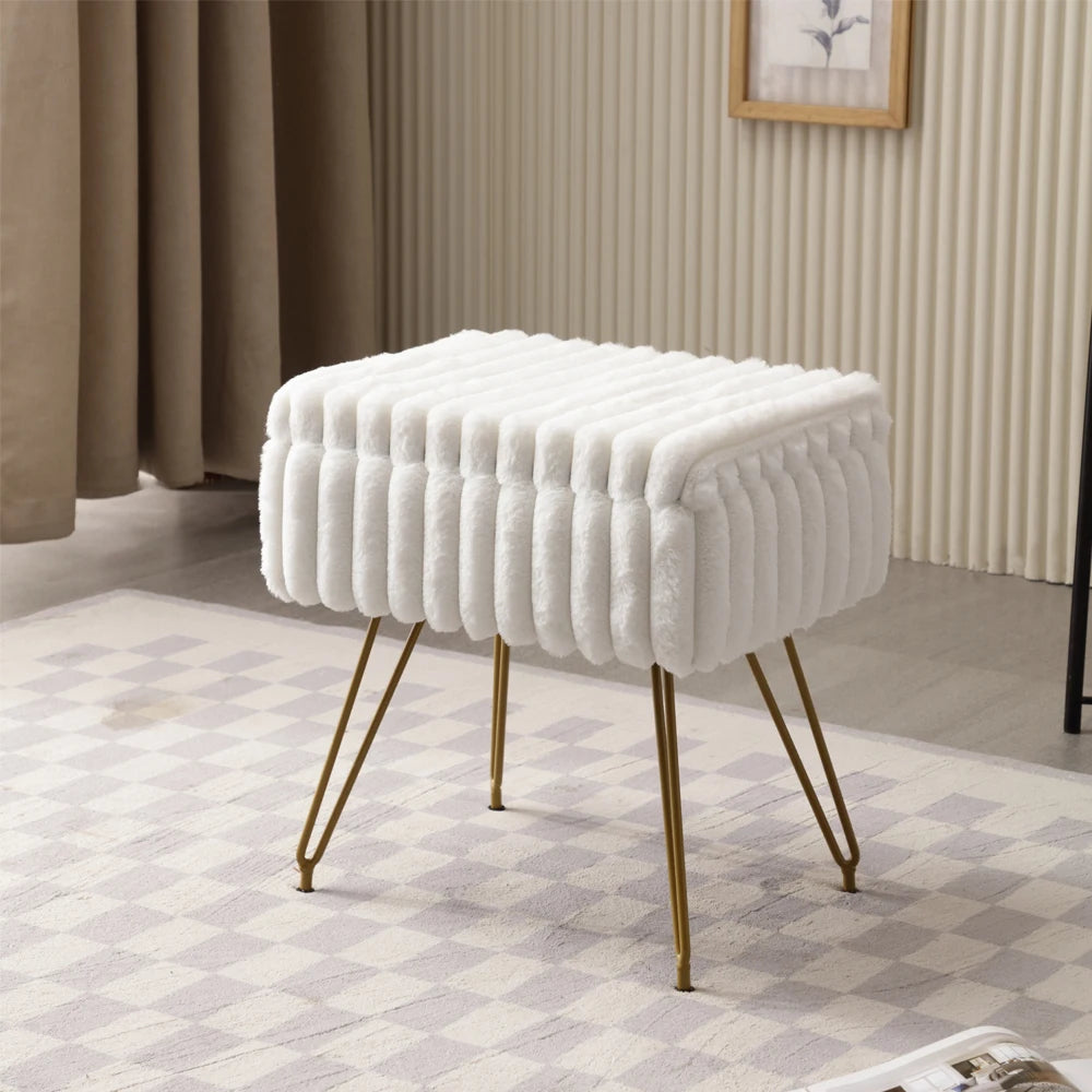 Pouf coffre blanc en fausse fourrure avec couvercle fermé et pieds dorés, posé sur un tapis à motifs.