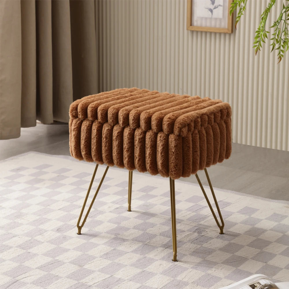 Pouf coffre marron caramel en fausse fourrure avec assise rectangulaire et pieds dorés, près de rideaux beiges.