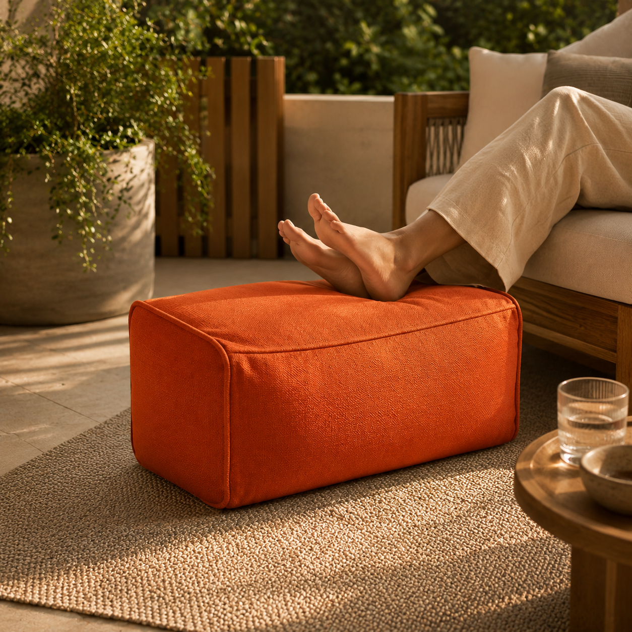 Personne reposant ses jambes sur un pouf extérieur rectangulaire orange