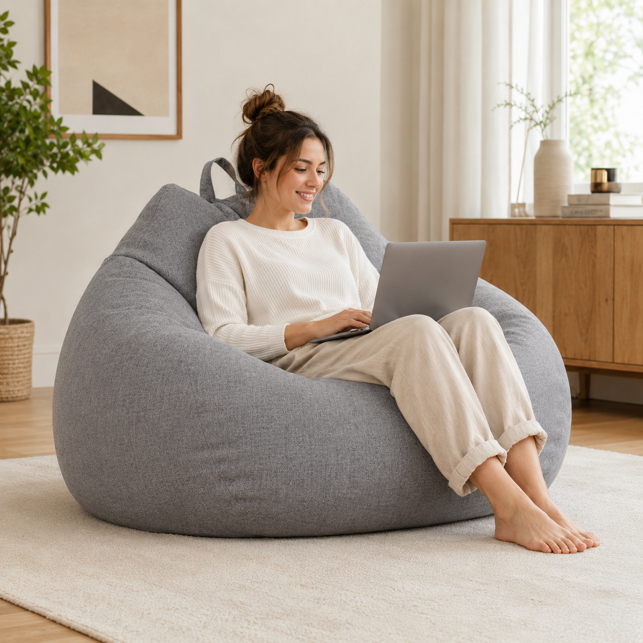 Femme installée avec un ordinateur dans un pouf poire géant en lin lavable