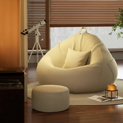 Pouf poire géant crème avec repose-pieds dans un salon chaleureux