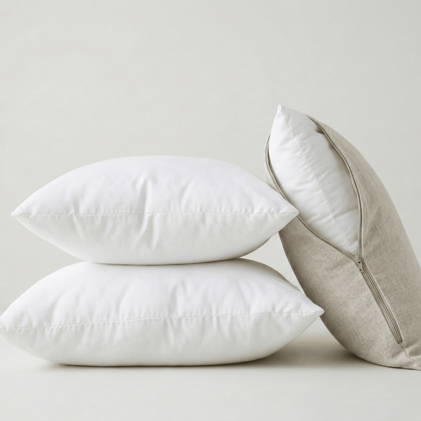 Inserts de coussin blancs empilés avec housse en lin beige ouverte – rembourrage carré prêt à être utilisé avec une housse