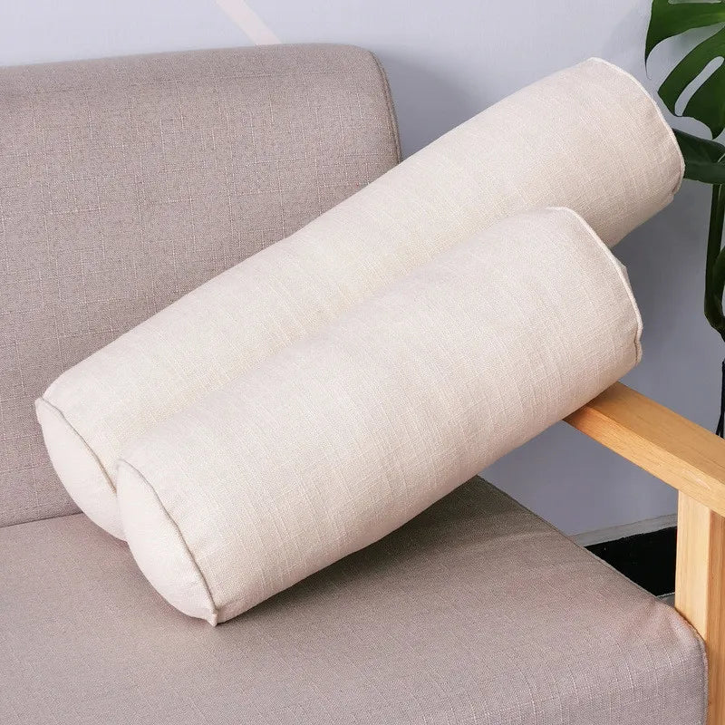 Deux coussins boudins beige clair avec extrémités passepoilées sur un fauteuil