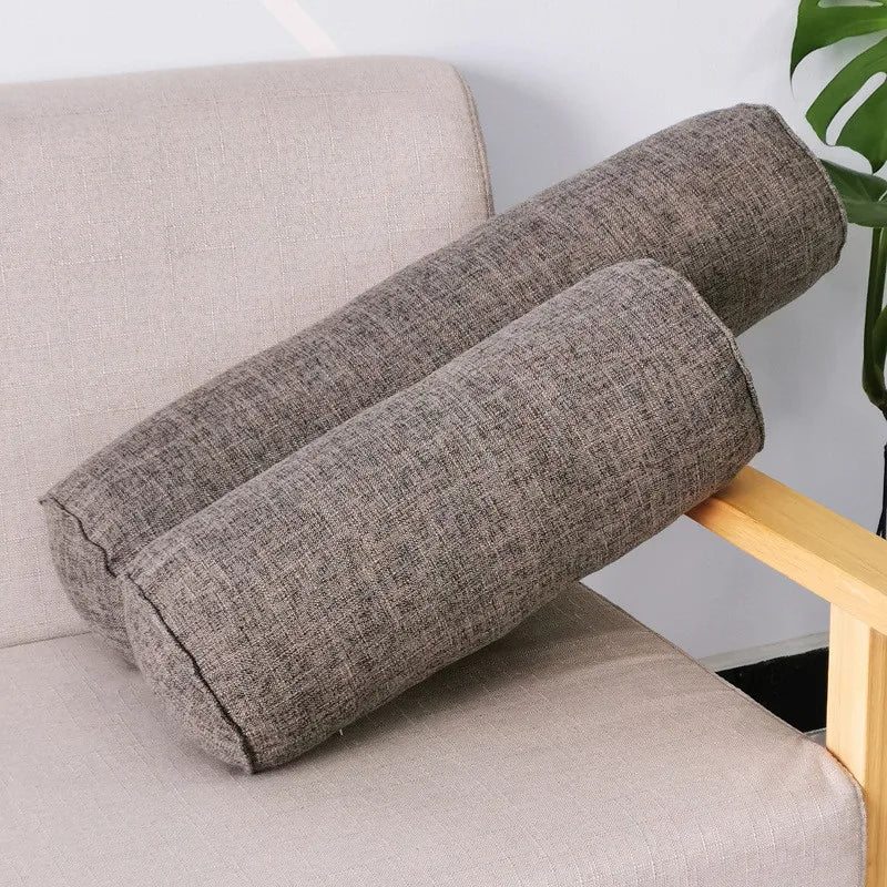 Deux coussins boudins gris foncé en tissu chiné posés sur un fauteuil beige