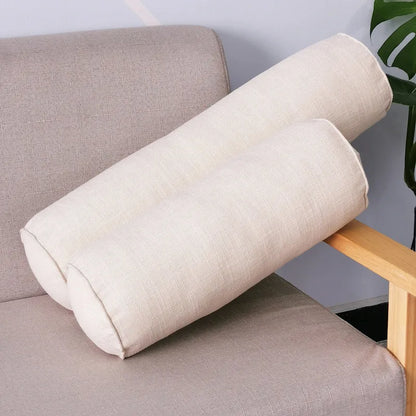 Deux coussins cylindriques beige clair en tissu chiné posés sur un fauteuil