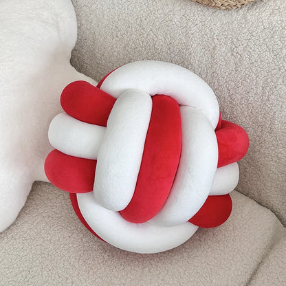 Coussin nœud bicolore en velours blanc et rouge sur un canapé clair