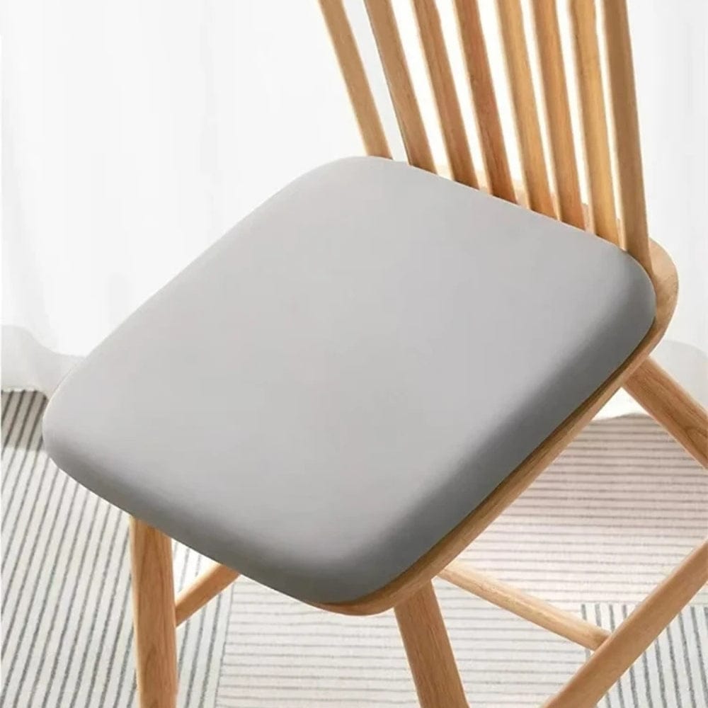 Coussin de chaise en tissu gris, forme carrée, posé sur une chaise en bois dans un intérieur moderne