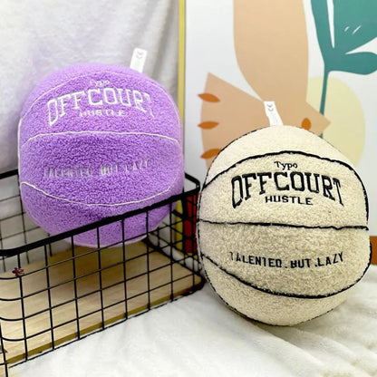 Coussins décoratifs en forme de ballon de basket, un violet et un beige, posés dans un panier