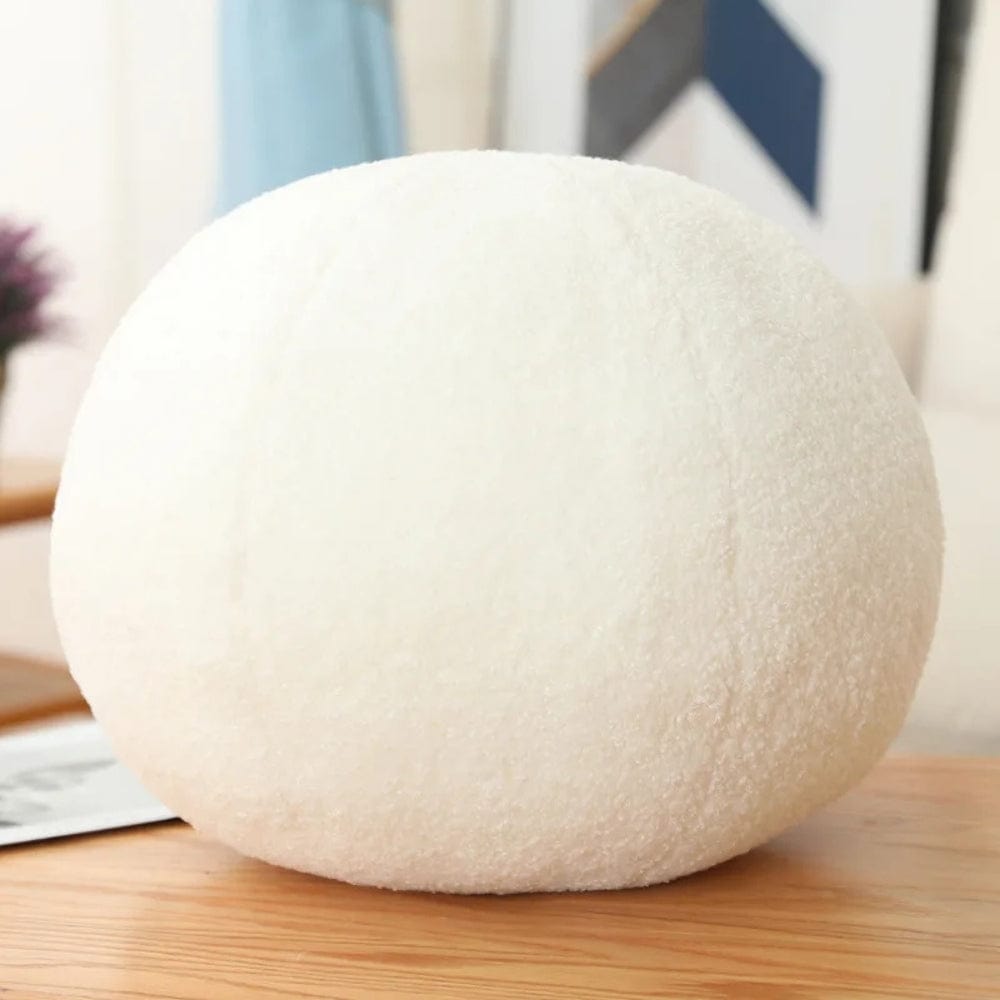 Coussin boule blanc en matière douce, posé sur une table en bois, idéal pour la décoration intérieure