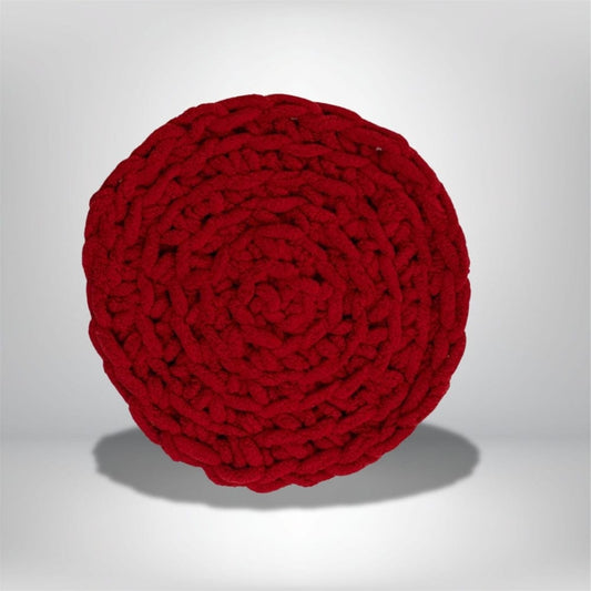 Coussin rond en velours rouge avec un motif tressé, posé sur un fond neutre, idéal pour un canapé ou une