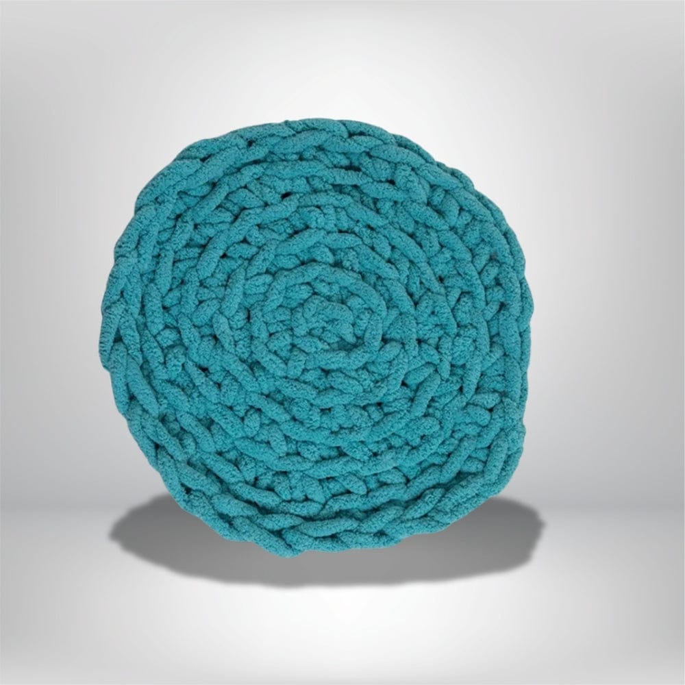 Coussin déco rond en tissu tressé turquoise, posé sur une surface neutre, idéal pour un salon moderne