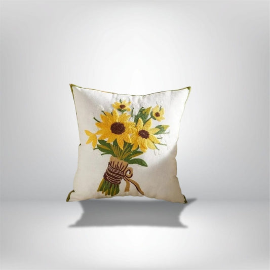 Coussin décoratif en coton blanc avec motif de tournesols brodés, posé sur un fond neutre