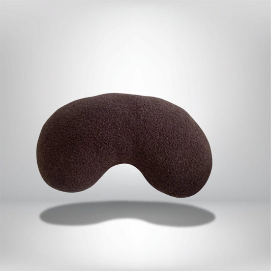 Coussin décoratif en forme de haricot, couleur marron, en tissu doux, posé sur un fond neutre