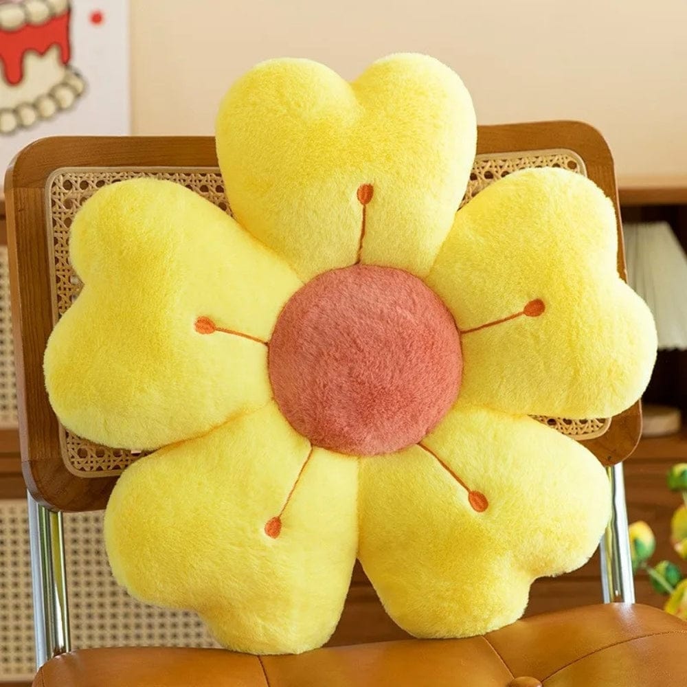 Coussin décoratif en forme de fleur, jaune avec un cœur rose, posé sur une chaise en bois