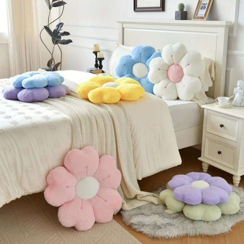 Coussins décoratifs en forme de fleurs aux couleurs pastel, posés sur un lit avec une couverture beige
