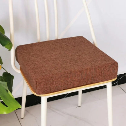 Coussin carré en tissu marron sur une chaise blanche, ajoutant une touche chaleureuse à la décoration intérieure