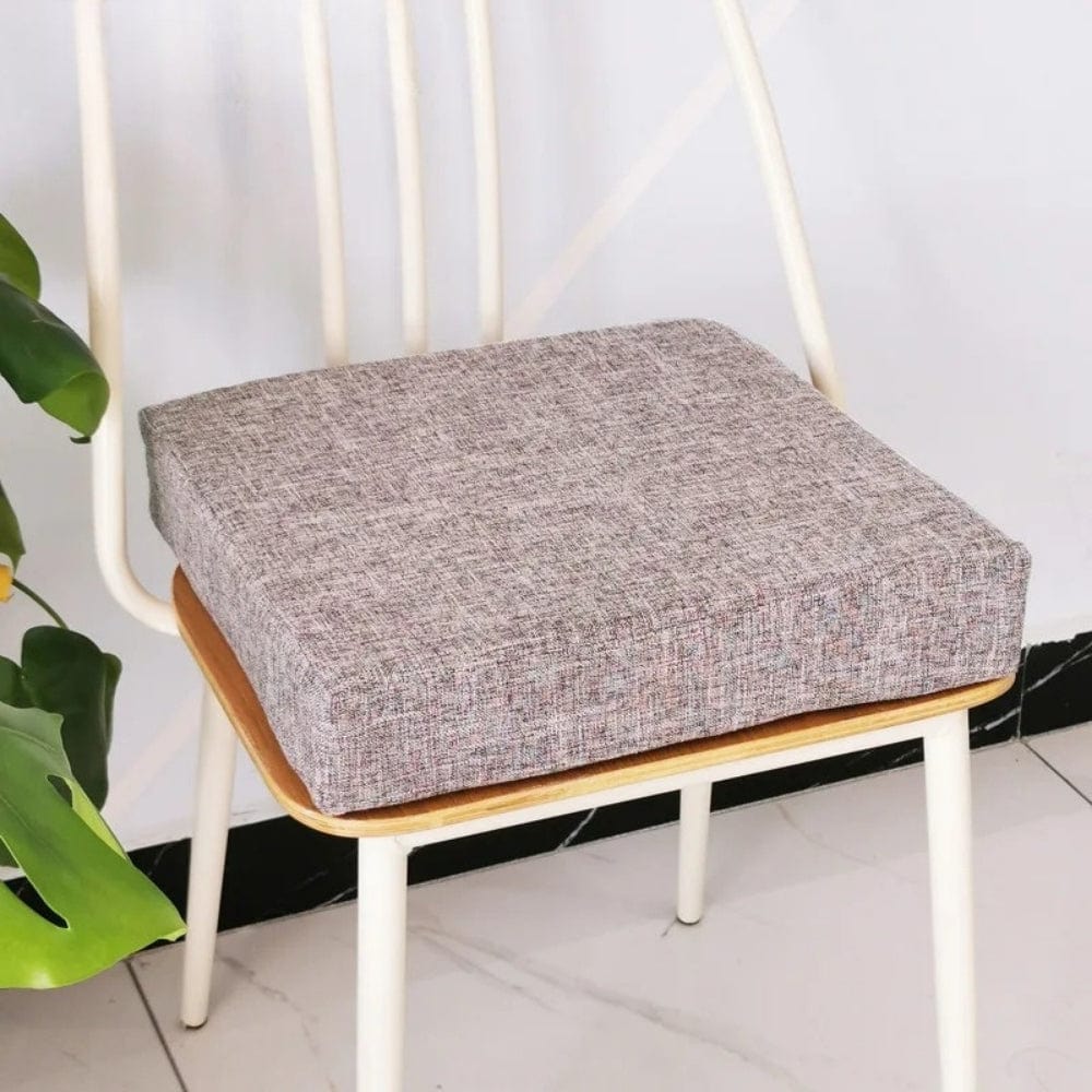 Coussin de chaise carré en tissu gris texturé, posé sur une chaise en bois avec des pieds métalliques
