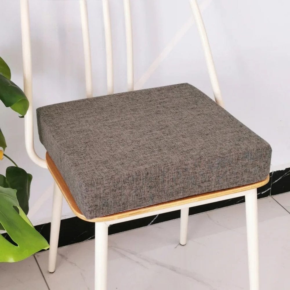 Coussin carré en tissu gris, posé sur une chaise en bois, ajoutant une touche de confort à la décoration