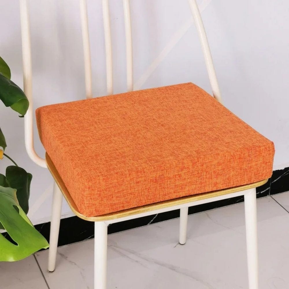 Coussin carré orange en tissu texturé posé sur une chaise moderne dans un intérieur lumineux