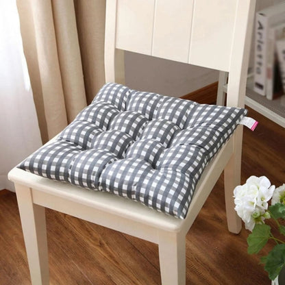 Coussin de chaise de jardin à motifs carreaux gris et blanc, posé sur une chaise en bois dans un intérieur