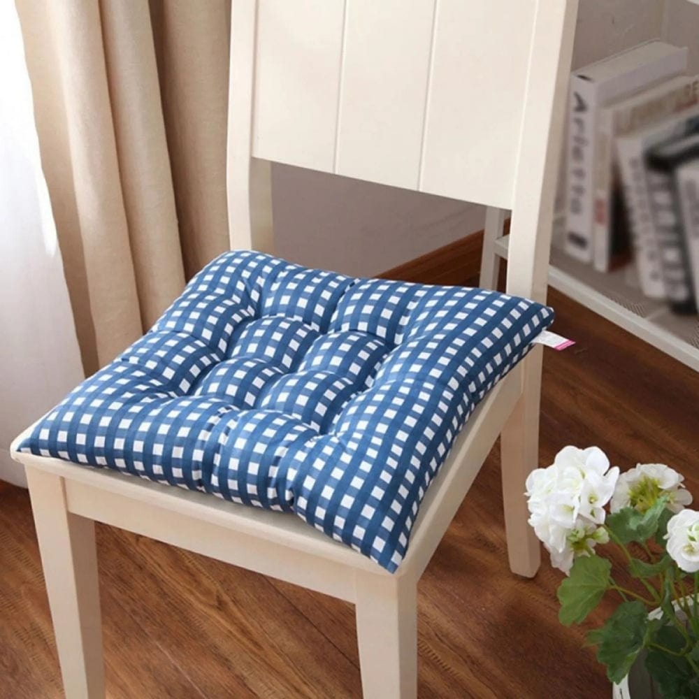 Coussin de chaise bleu à carreaux blancs, placé sur une chaise en bois dans un intérieur chaleureux