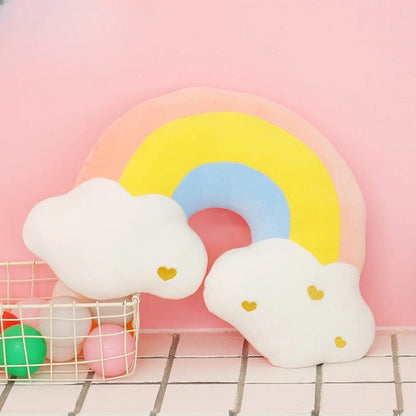 Coussin décoratif en forme d'arc-en-ciel pastel avec des nuages blancs, idéal pour une chambre enfantine