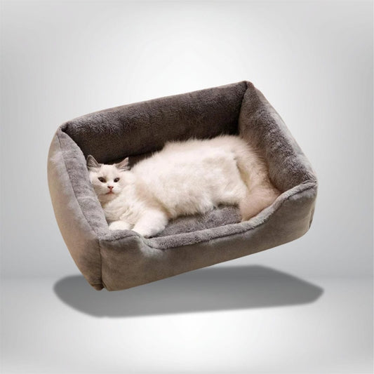 Coussin de chat en velours gris, avec un intérieur doux, posé sur un fond neutre