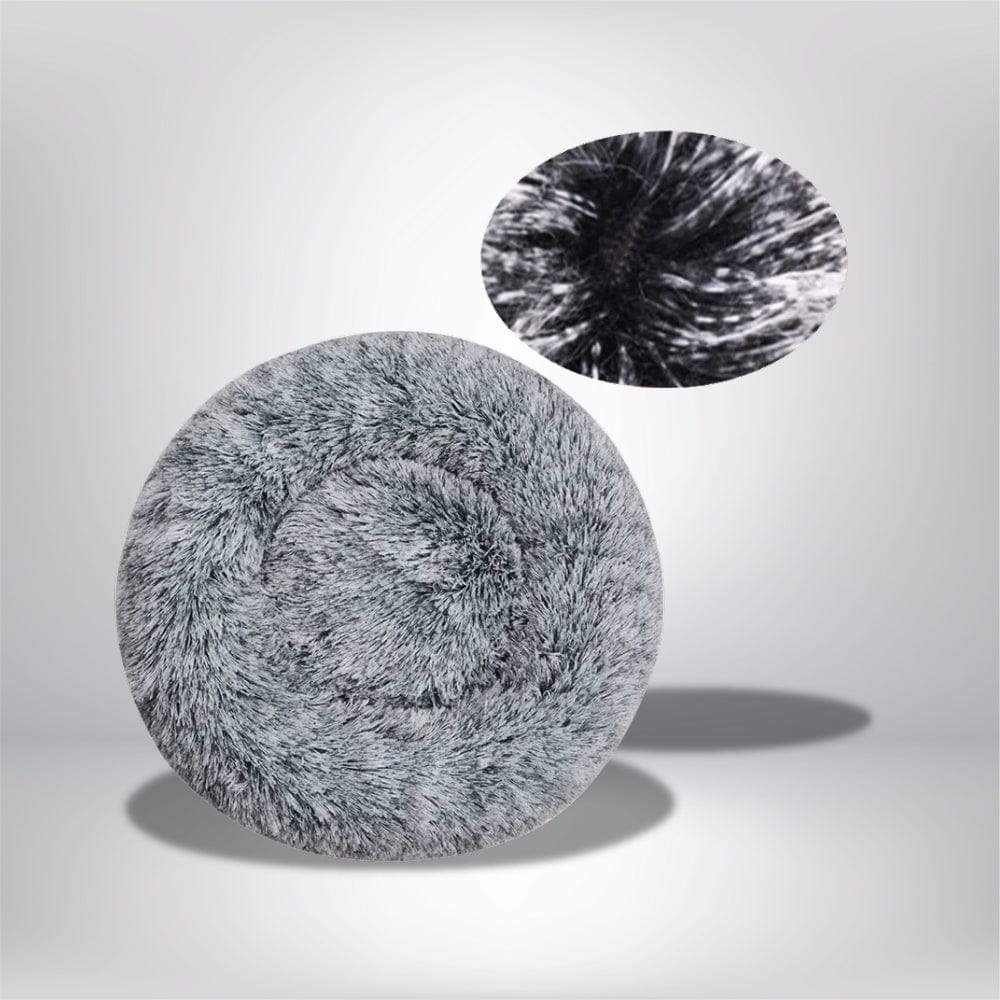 Coussin décoratif rond en fausse fourrure grise, posé sur un fond neutre, idéal pour un salon ou une chambre