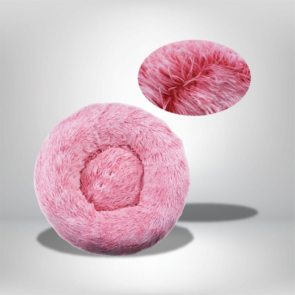 Coussin décoratif rond en fausse fourrure rose, posé sur un fond neutre, idéal pour un coin douillet