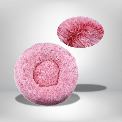 Coussin décoratif rond en fausse fourrure rose, posé sur un fond neutre, idéal pour un coin douillet
