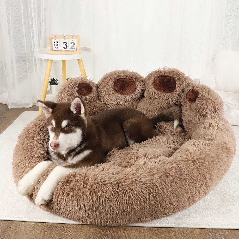 Coussin de chien XXL en peluche marron, forme ronde, installé sur un sol en bois clair avec un décor moderne