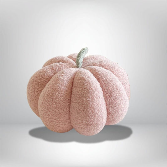 Coussin décoratif en forme de citrouille rose, doux au toucher, posé sur un fond neutre